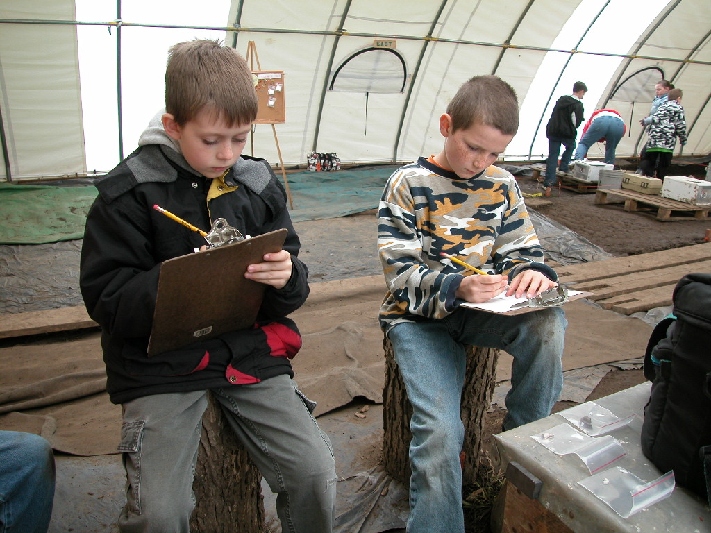 Two students carefully document their discoveries from the day
